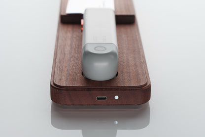 Gray electronic device on a wooden charging pad with a white background